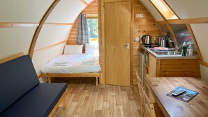 A cozy, compact room with a bed, a small kitchenette, and a table with a magazine.