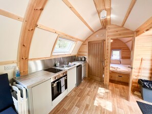 Een kleine keuken met een spoelbak, fornuis en een raam boven het aanrecht.