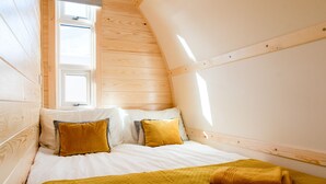 Een gezellig slaapkamer met schuine dak en een bed, kussens en een dekbed.