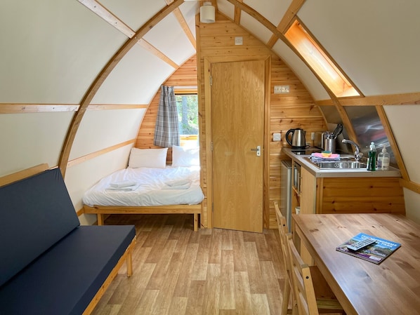 Een gezellig, compacte kamer met een bed, een kleine kitchenette en een tafeltje met een tijdschrift.