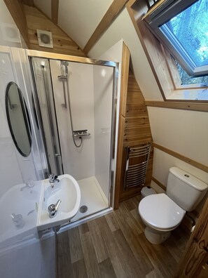 A compact bathroom with a shower, sink, toilet, and skylight. - Woodland Escape in a Cosy Glamping Cabin (Tomintoul)