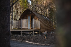 A wooden cabin with a balcony, surrounded by trees.