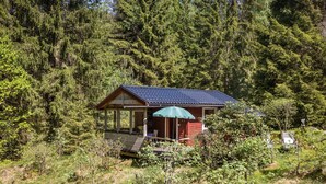 A small cabin with a porch and a green umbrella, surrounded by dense forest. - Dammeberg by Interhome (Karl Gustav)