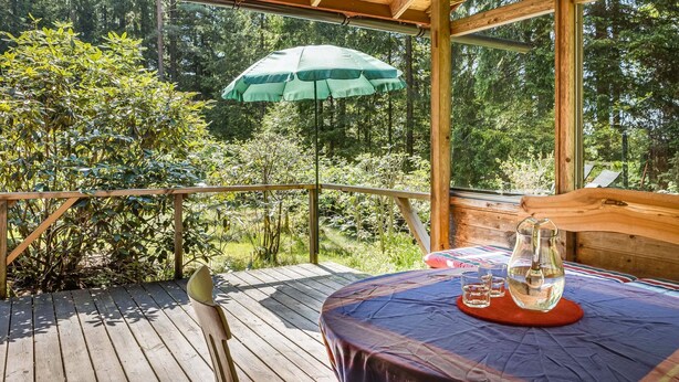 A wooden deck with a table and chairs, an umbrella, and a glass of water. - Dammeberg by Interhome (Karl Gustav)