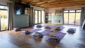 A spacious room with wooden floors and large windows, featuring yoga mats and folded towels. - Rustic Coastal Cabin with Wood Fired Hot Tub (Cockburnspath)