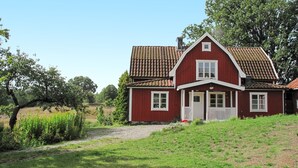 Une maison rouge avec un toit en tuiles, des boiseries blanches et un petit porche.