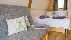 Ein gemütliches Schlafzimmer mit einem Bett, einem grauen Sofa und einer Zeitschrift darauf.