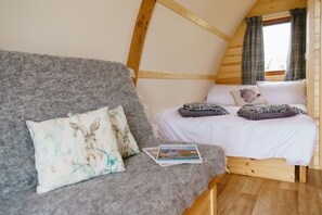 Un dormitorio tipo loft acogedor con una cama en altillo, un sofá gris y una revista sobre el sofá.
