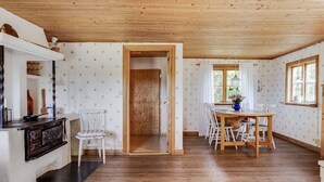 A wooden-paneled room with a dining area, a kitchen counter, and a door leading to another room. - Måbäcken by Interhome (Torestorp)