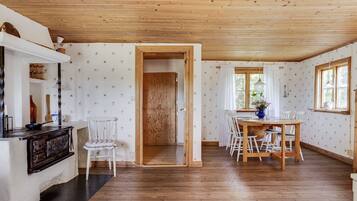 A wooden-paneled room with a dining area, a kitchen counter, and a door leading to another room.