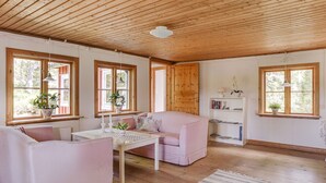 A cozy room with wooden flooring, a pink sofa, a white table, and a bookshelf. - Måbäcken by Interhome (Torestorp)