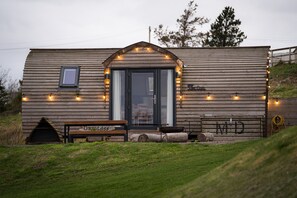 A small wooden cabin with a front porch, a bench, and a small table. - Coastal Family Cabin with Wood Fired Hot Tub (Cockburnspath)