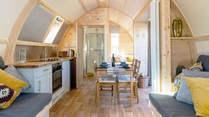 Een gezellig, compact leefruimte met een keuken, eethoek en zithoek, met houten constructie en een schuine kap.