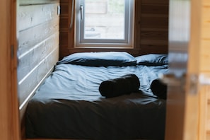 A narrow room with a bed, a window, and wooden walls. - Coastal Family Cabin with Wood Fired Hot Tub (Cockburnspath)