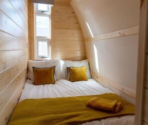 Ein kleines, gemütliches Schlafzimmer mit geneigter Decke und Holzwänden.