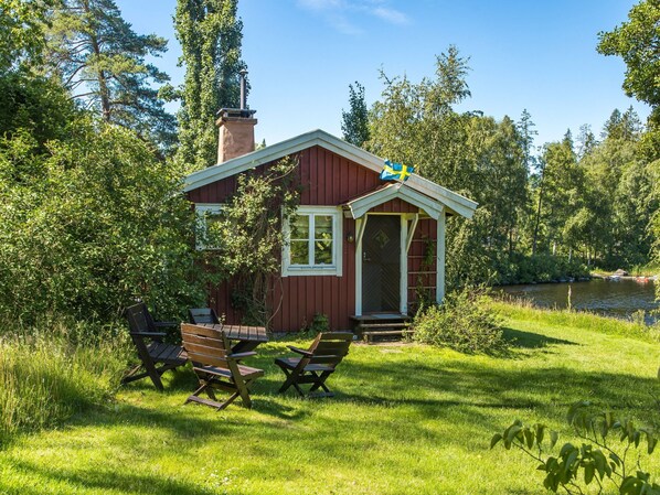 A small wooden cabin with a chimney, a porch, and a table with chairs.