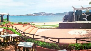 An outdoor seating area with tables and chairs, overlooking a beach and the sea. - Centro Vacanze Isuledda by Interhome (Cannigione)