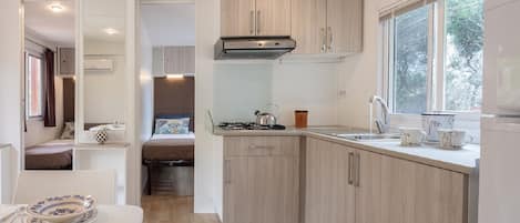 A compact kitchen with wooden cabinets, a gas stove, and a window providing natural light.
