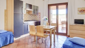 A compact kitchen with modern appliances, a dining area with a table and chairs, and a balcony with a view.