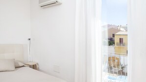 A bedroom with a bed, a bedside table, a lamp, and a window with curtains.