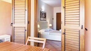 A hotel room with a bed, bedside lamps, a framed picture on the wall, and a wooden table in the foreground.