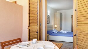Una habitación con una cama, una mesa lista para dos personas y una puerta de madera.