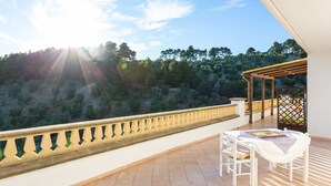 Una terraza con una mesa y sillas, con vistas a una colina arbolada.