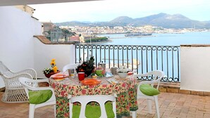 A balcony with a table set for two, overlooking a coastal cityscape with mountains in the distance. - Casa Belvedere by Interhome (Gaeta)