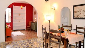 A dining area with a wooden table, chairs, and a tiled floor. There is a red wall and a white wall with a painting. - Casa Belvedere by Interhome (Gaeta)