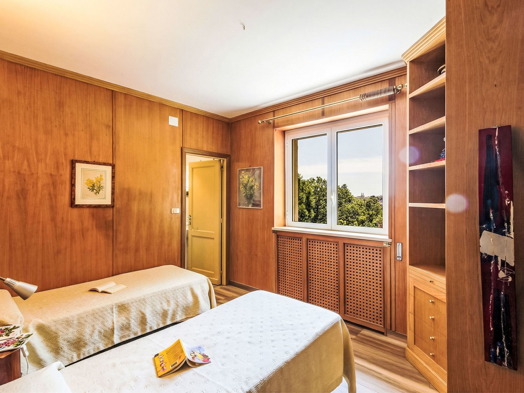 Ein Zimmer mit Holzwänden, einem Bett mit weißer Bettdecke, einem Fenster mit Ausblick und einem Holzschrank.