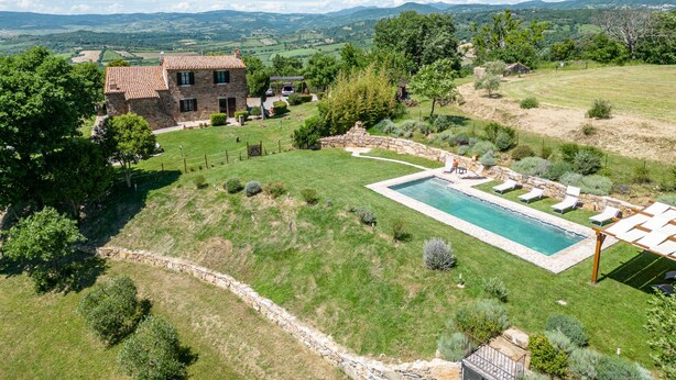 Una casa de piedra con piscina y zona de estar al aire libre.