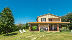 A two-story house with a stone facade, a tiled roof, and a covered porch.