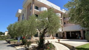 Un hôtel à plusieurs étages doté d’une cour intérieure agrémentée d’un arbre et de parterres de fleurs.