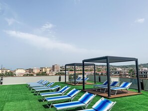 A rooftop terrace with multiple lounge chairs and a pergola structure. - Santa Costanza by Interhome (San Vincenzo)