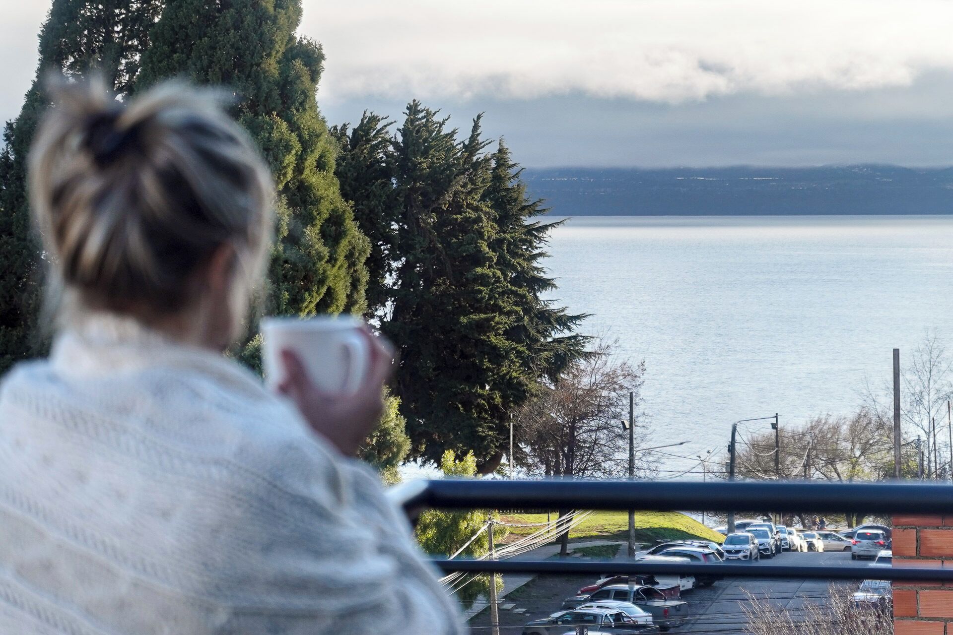 A person overlooking a parking lot with a view of a body of water and trees.