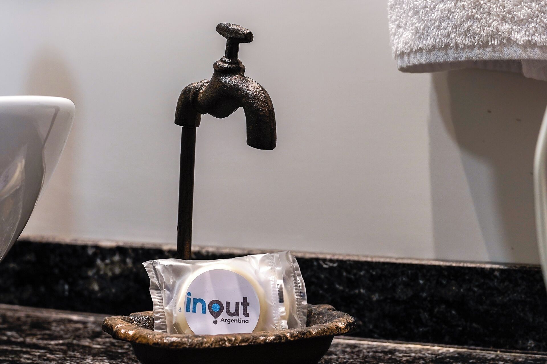 A bathroom sink with a faucet, a soap dispenser, and a towel rack.