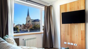 Una habitación moderna con un ventanal grande, un radiador, un panel de pared de madera y un televisor de pantalla plana.