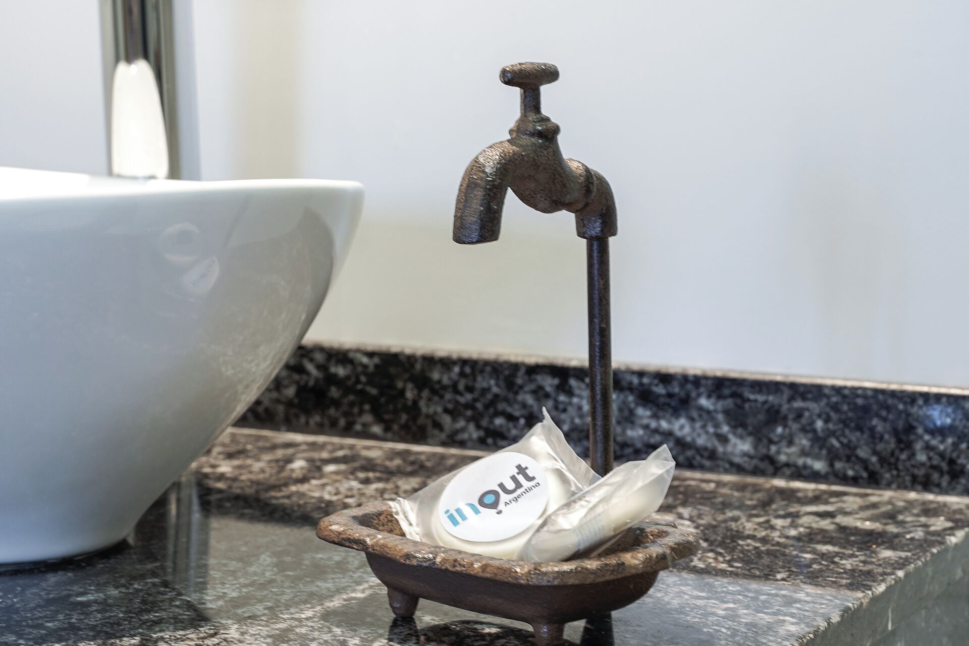 Un lavabo de baño con un recipiente pequeño que contiene un dispensador de jabón y una botella.