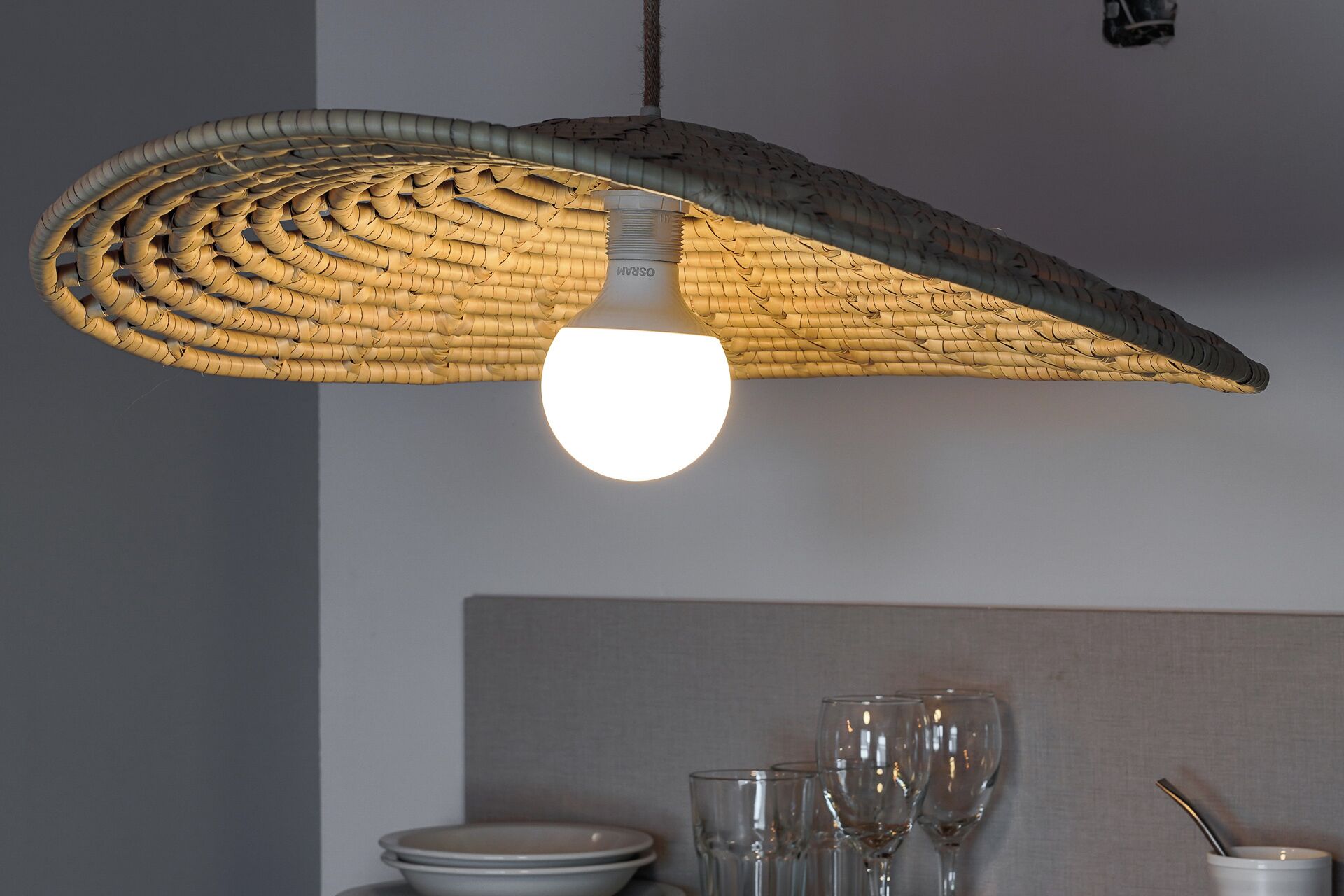 Een geweven lamp met een gloeilamp aan het plafond.