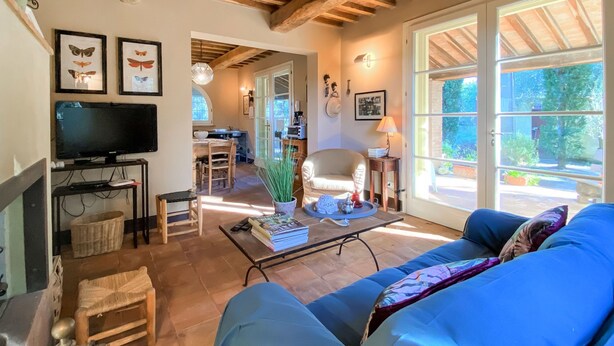 A cozy living room with a sofa, a television, and a dining area with a table and chairs. - Vacation home Erbe by Interhome (Montescudaio)