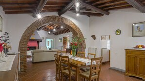 A dining area with a brick archway, wooden dining table, and chairs.