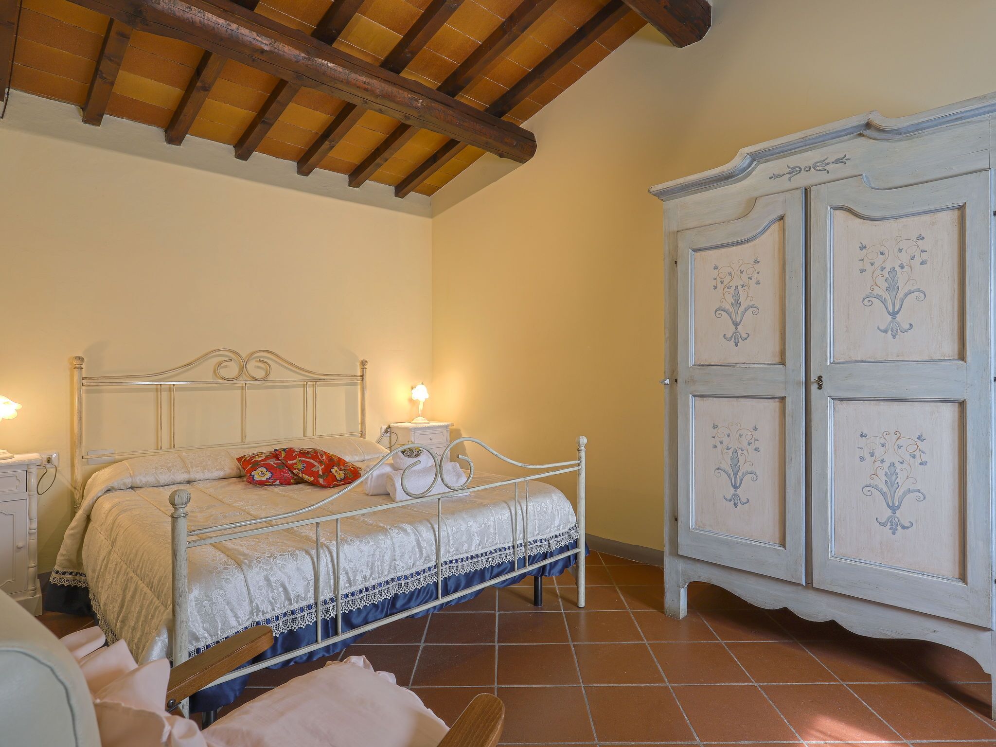 Ein Schlafzimmer mit Bett, Nachttischen, einem Kleiderschrank und einem Fliesenboden.