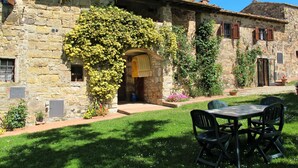 A stone building with a covered entrance, a grassy courtyard, and outdoor seating.