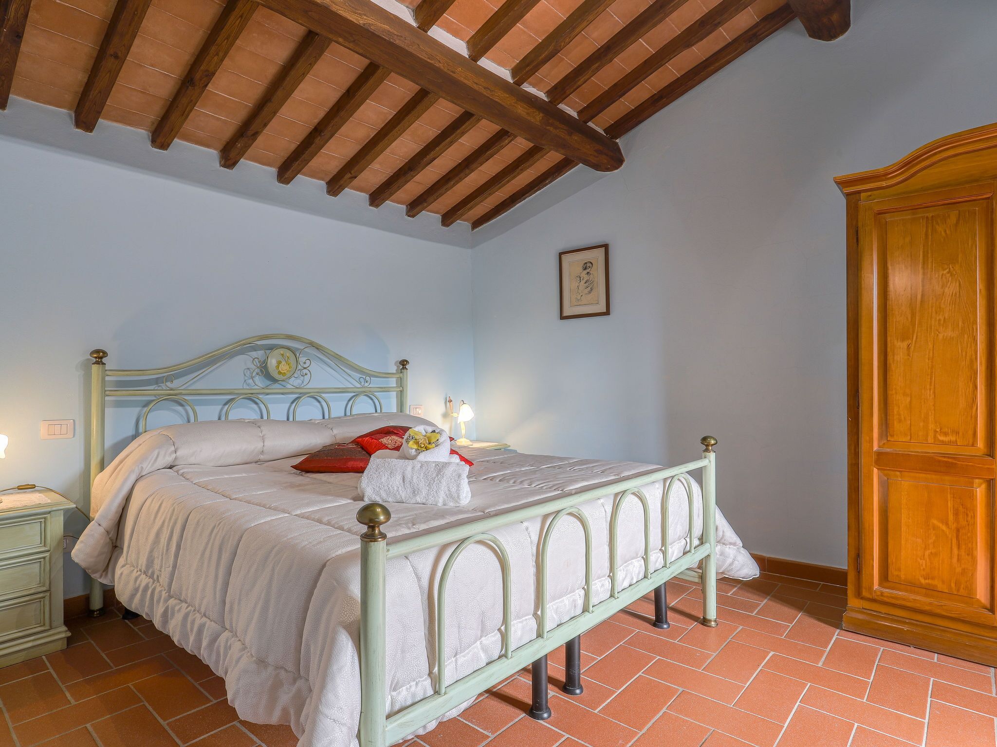 A bedroom with a bed, nightstand, and wooden wardrobe.