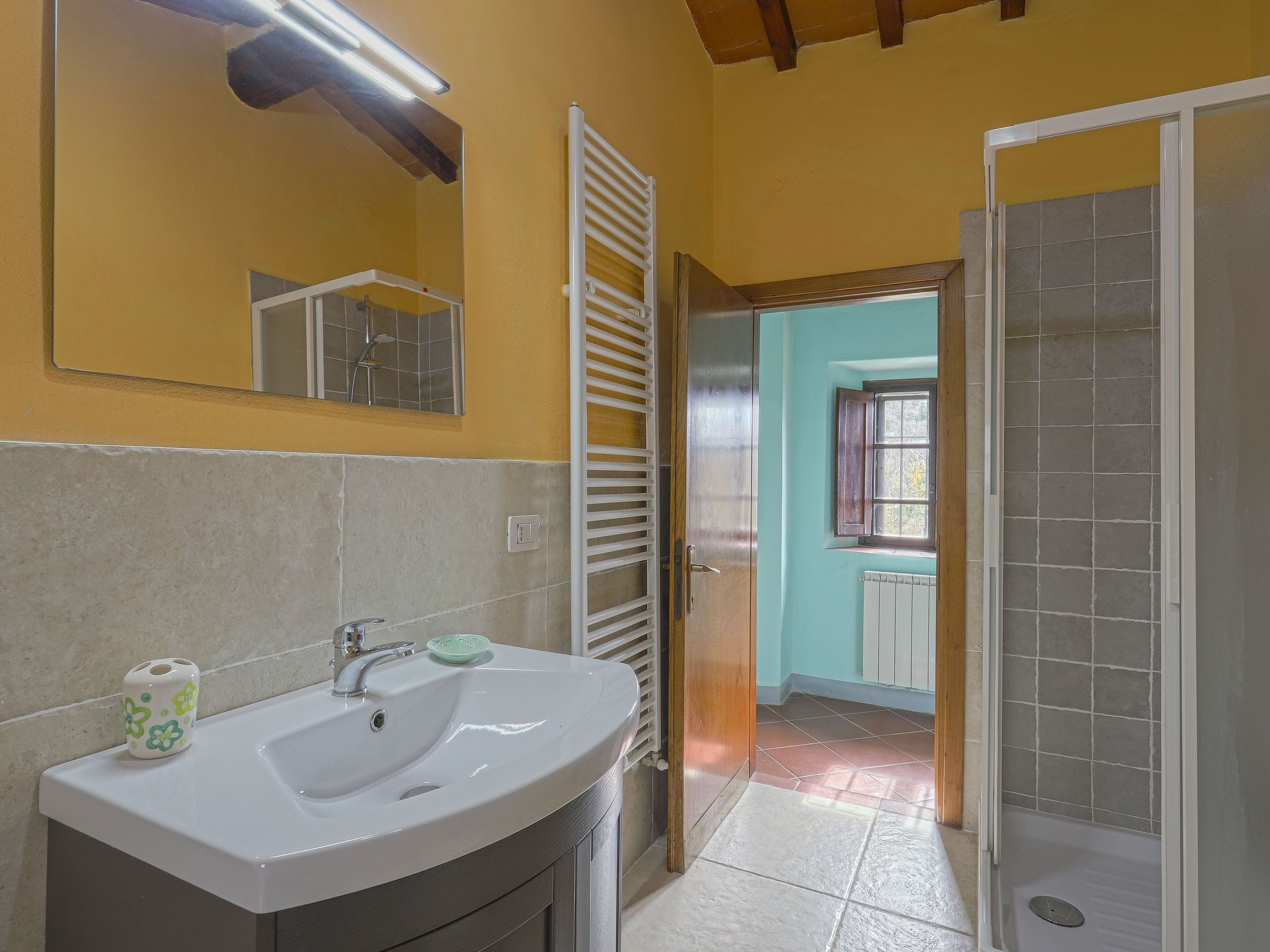 A bathroom with a white sink, a mirror, and a shower area.