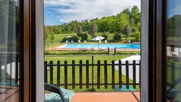 A view of a swimming pool with lounge chairs and umbrellas, surrounded by greenery and trees. - Podere Ritali by Interhome (Civitella in val di Chiana)