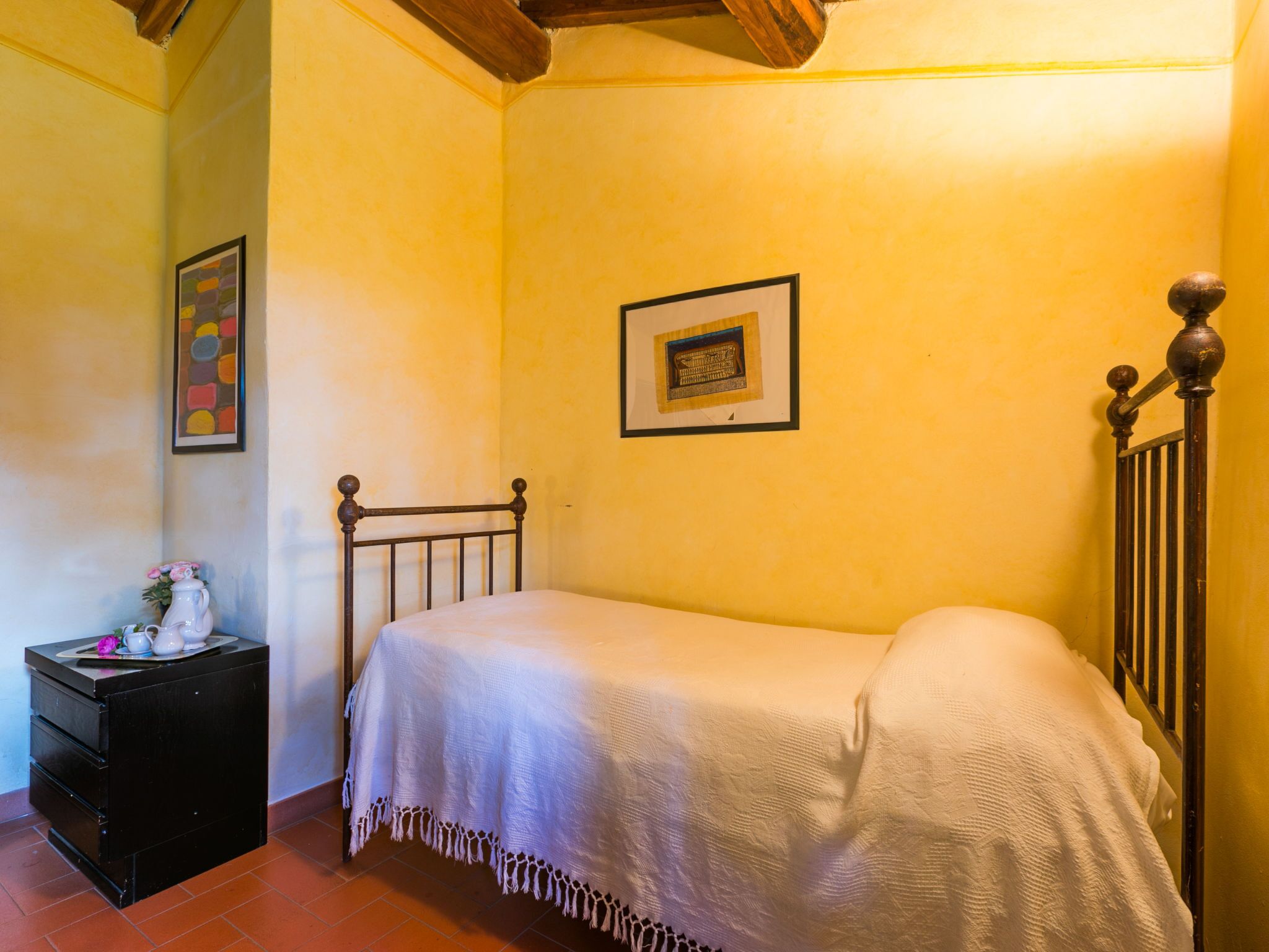 A small, cozy bedroom with a single bed, a nightstand, and a dresser.