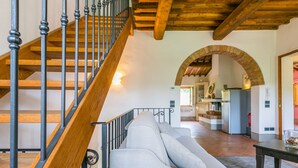 A staircase with wooden steps and metal balusters, leading to a living area with a sofa and a kitchen in the background. - Francigena by Interhome (Castelfiorentino)