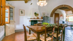 A rustic dining area with a wooden table, wicker chairs, and a hanging light fixture. - Francigena by Interhome (Castelfiorentino)