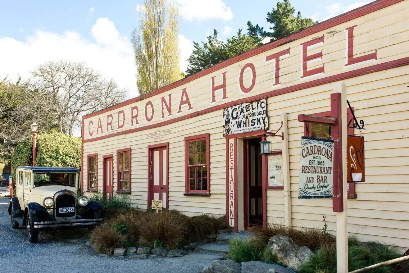 Un bâtiment historique portant l’inscription « Cardrona Hotel » et une enseigne indiquant « Gaelic Old Smuggle Whisky ».